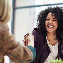 Poignée de main entre deux collaboratrices souriantes